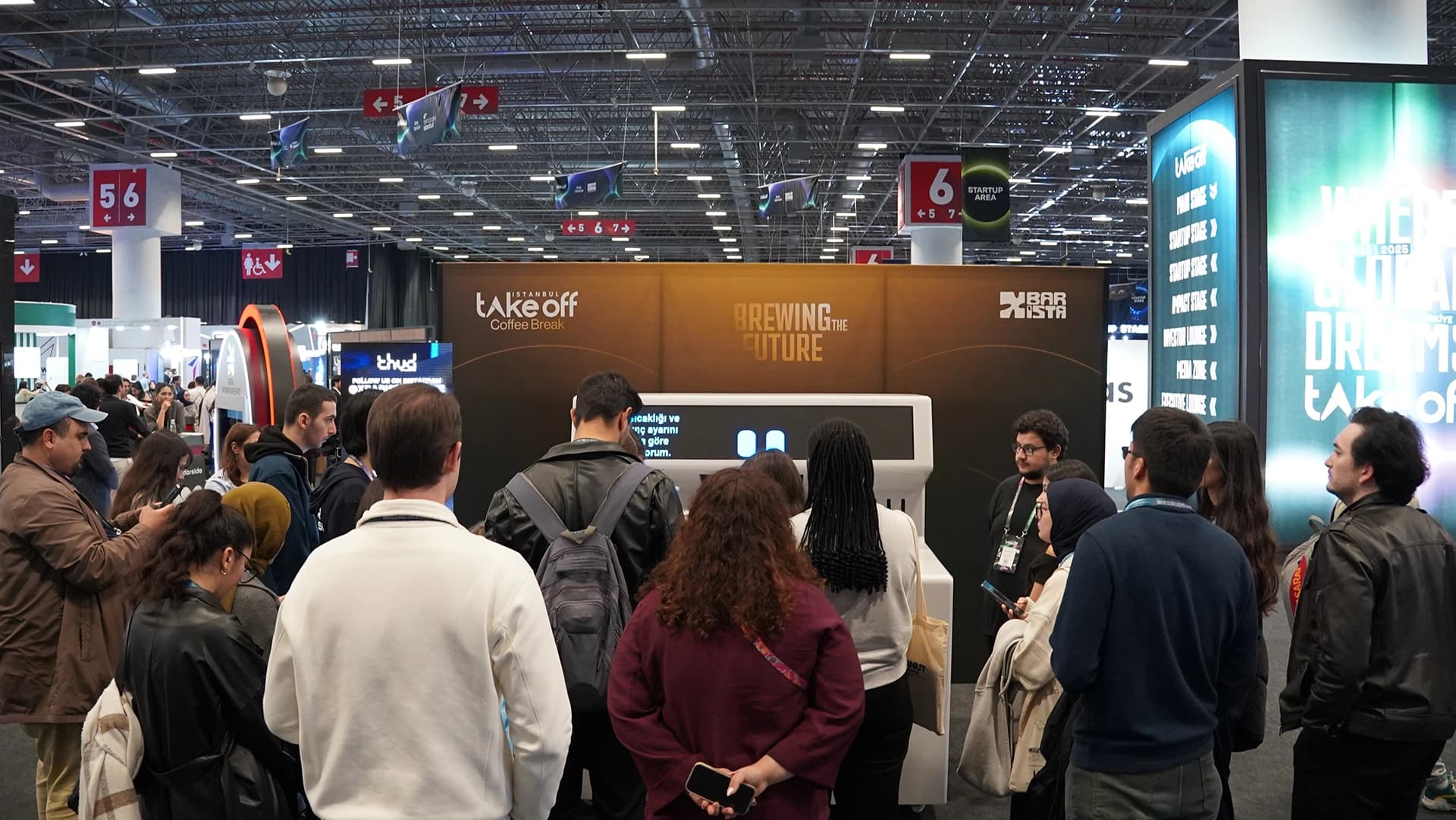 Uluslararası fuar stantında X Barista robot kol önünde büyülenmiş kalabalık